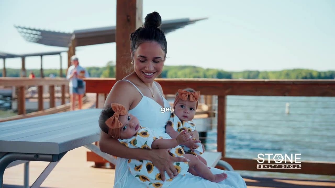 Jasmine Garcia seated on a lakeside dock, holding her infant twin daughters.
